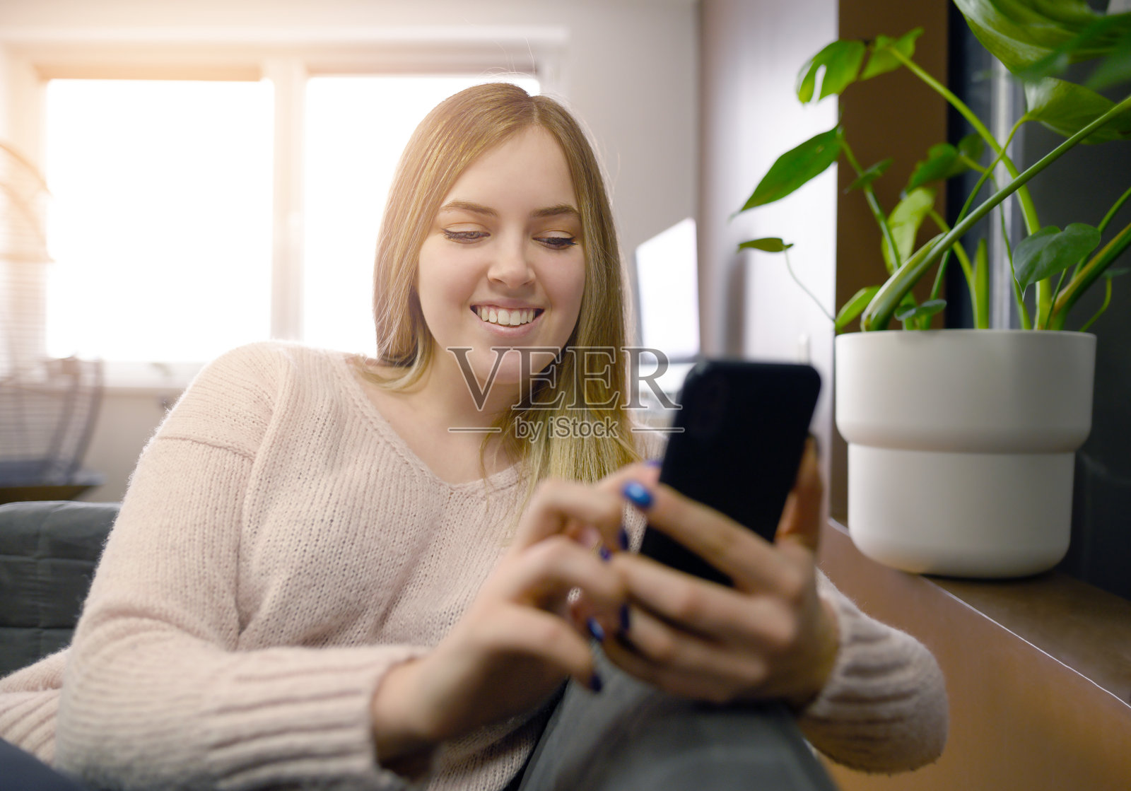 一名年轻女子坐在车厢里,手里拿着手机。照片摄影图片