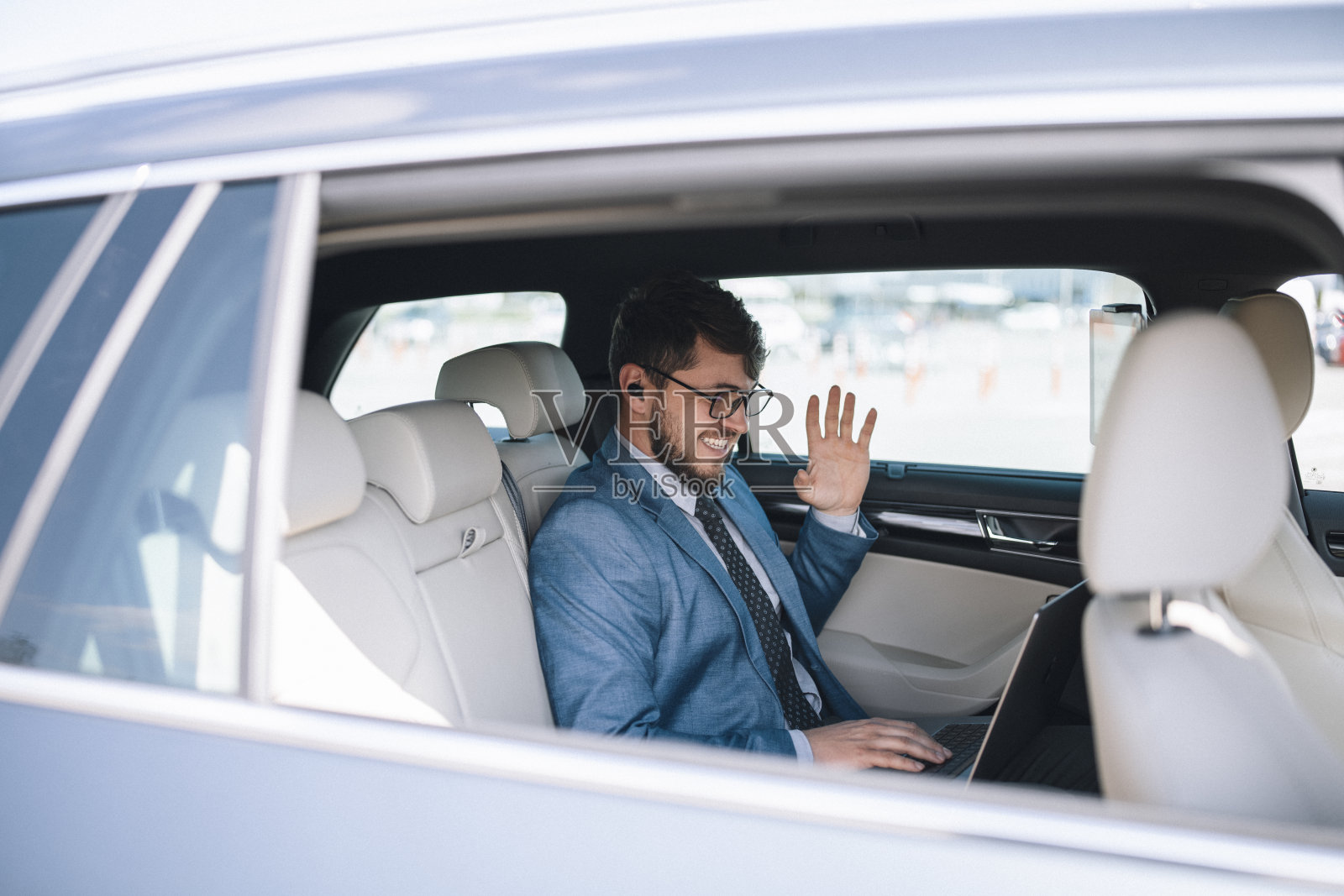 英俊的企业家在汽车后座上打视频电话。照片摄影图片