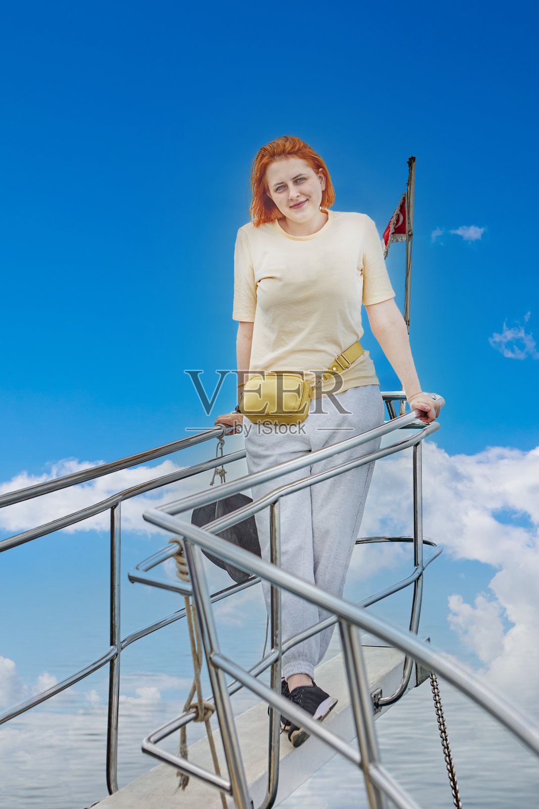 年轻的白人女子在观光游艇船头为摄影师摆姿势。照片摄影图片