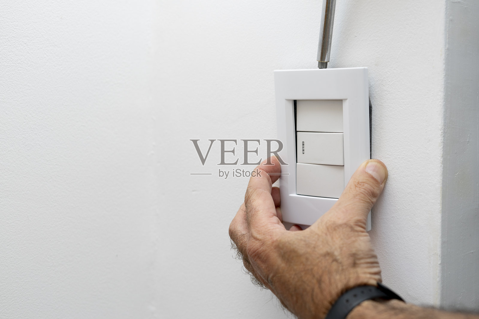 一个人的手拆除房子的电灯开关的框架照片摄影图片