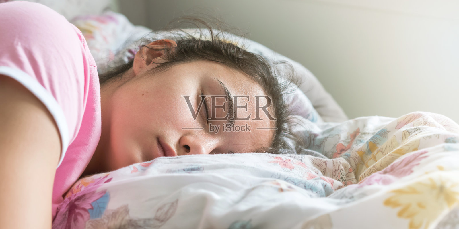 穿着t恤的女学生睡在大床上抱着枕头照片摄影图片