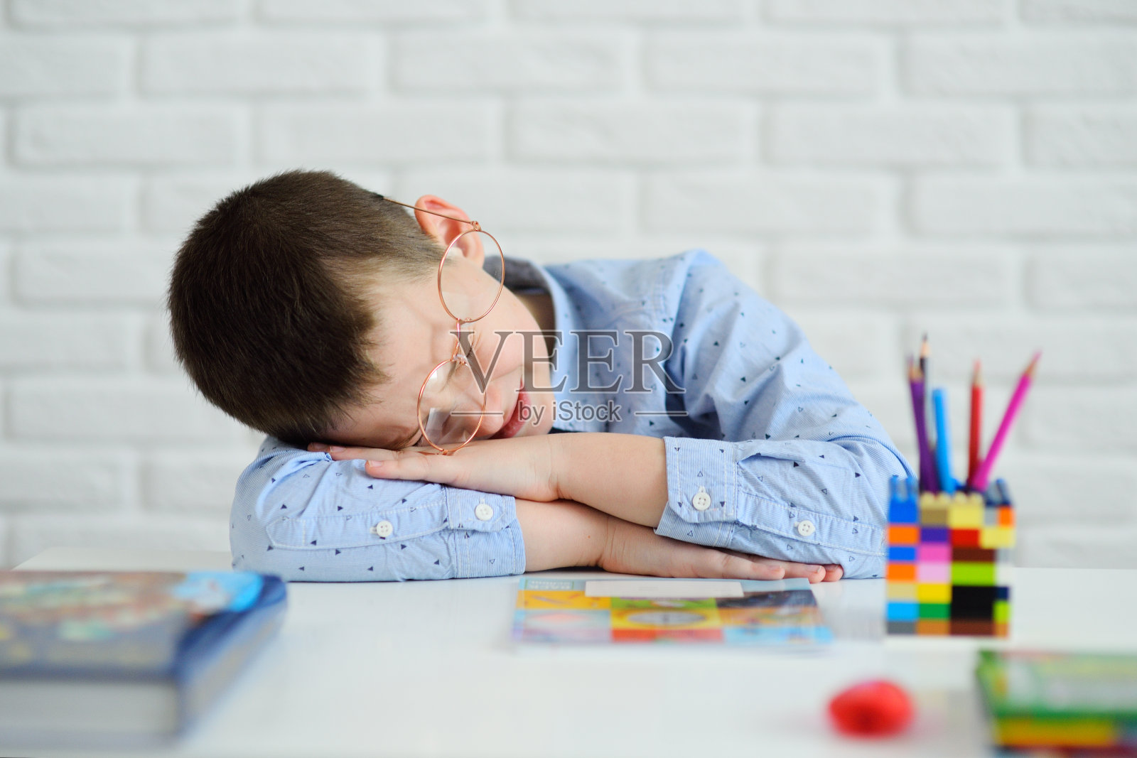 男学生厌倦学习,在书桌旁睡着了照片摄影图片