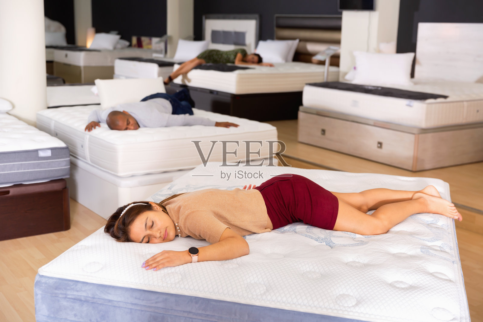一个年轻女子在家具店的新床垫上睡着了照片摄影图片