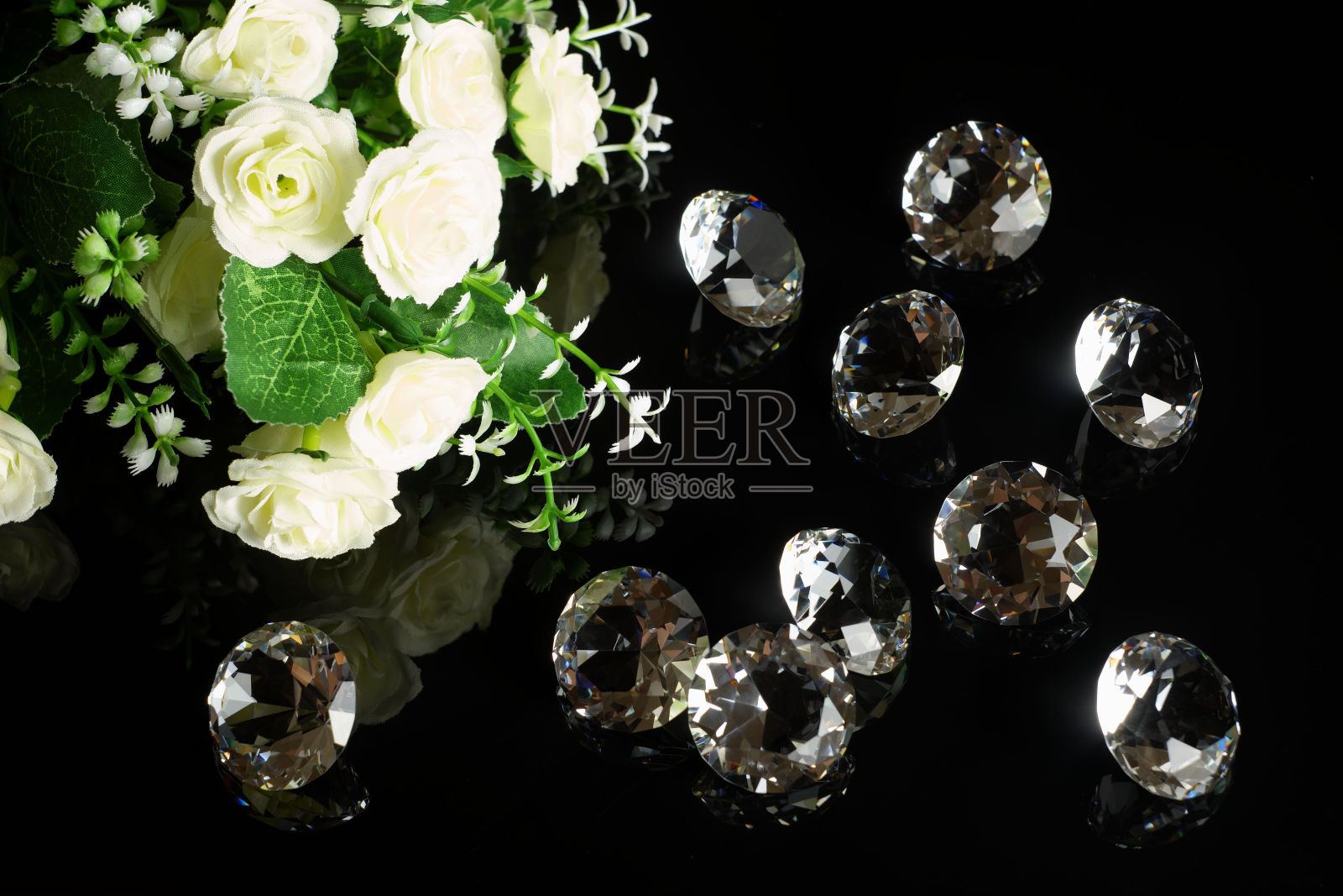 几颗优秀的纯钻石和白玫瑰花束反射在黑镜背景近景。珠宝钻石销售,邀请,行动,折扣横幅,海报模板照片摄影图片