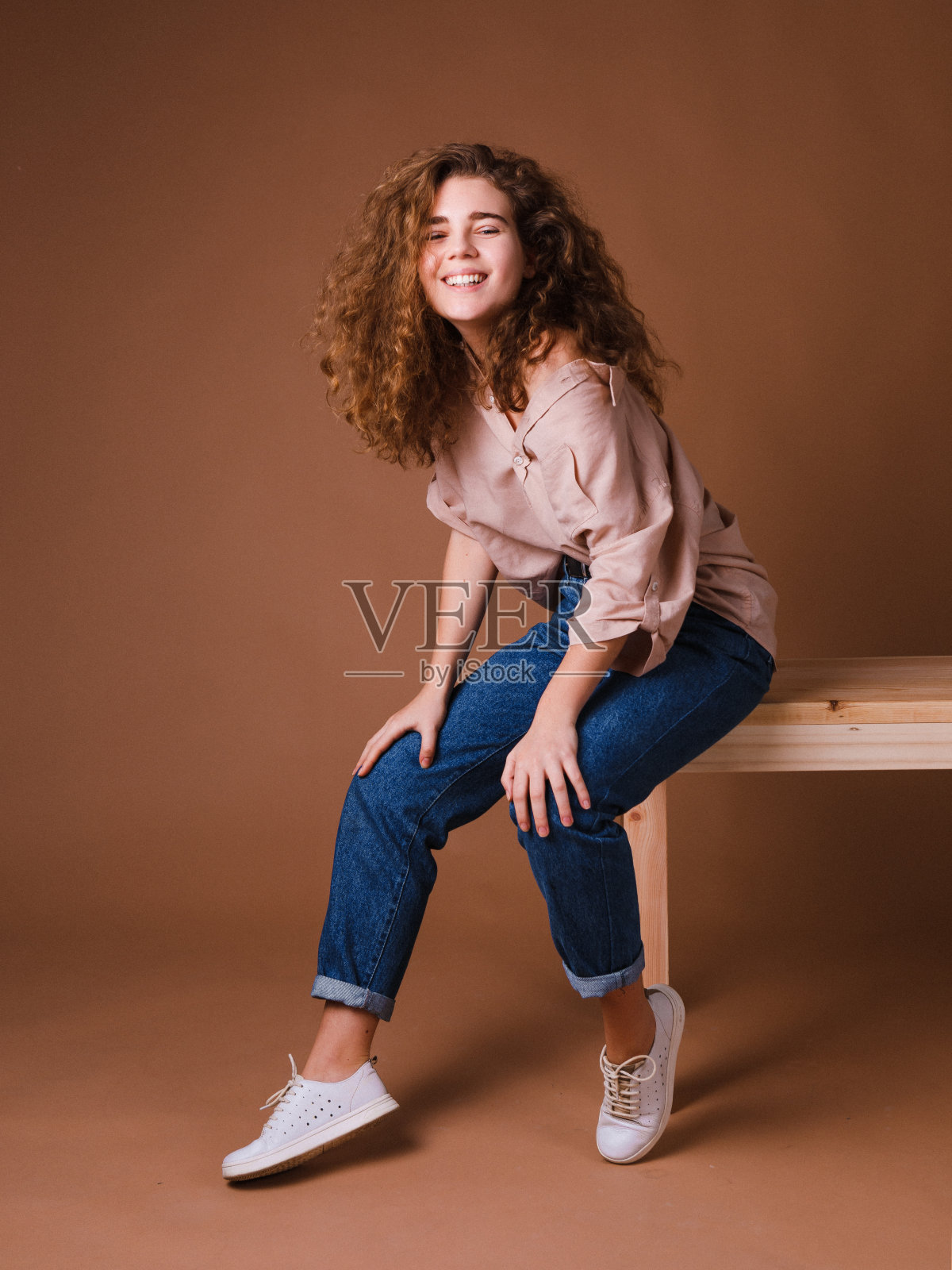 年轻情绪化的女人,卷着一头秀发,穿着时髦的衣服照片摄影图片