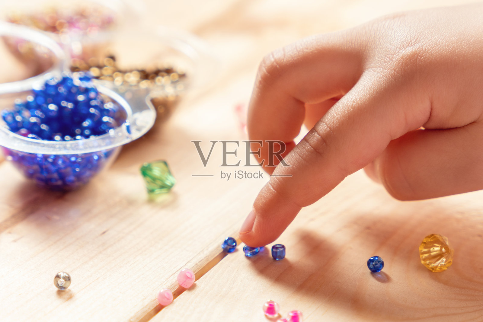 这个孩子用自己的双手制作珠宝,用线串起五颜六色的珠子照片摄影图片