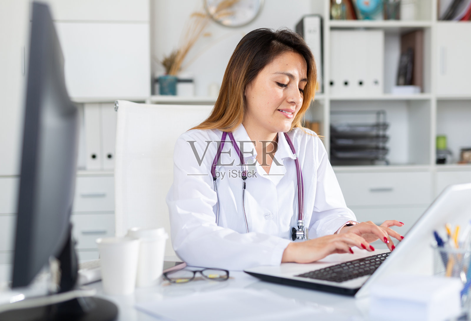 穿制服的医生在诊所用笔记本电脑工作照片摄影图片