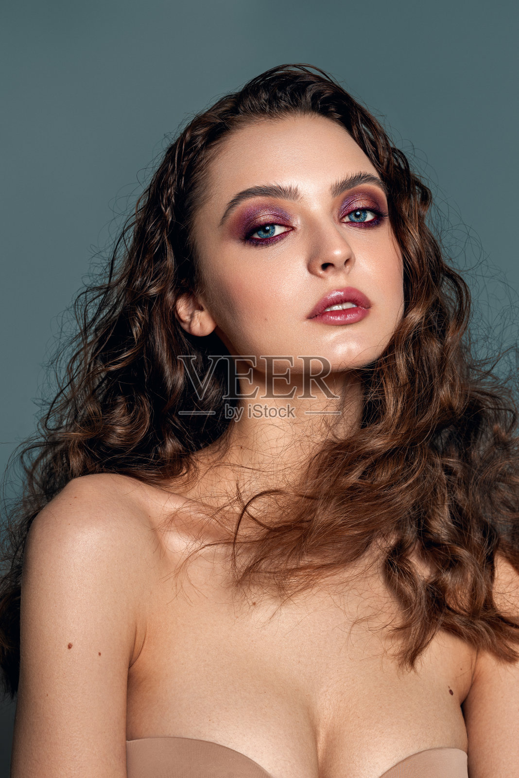 一个沉思的美丽的模特,有着别致的自然卷曲的头发。亮丝的头发。晚上化妆。照片摄影图片