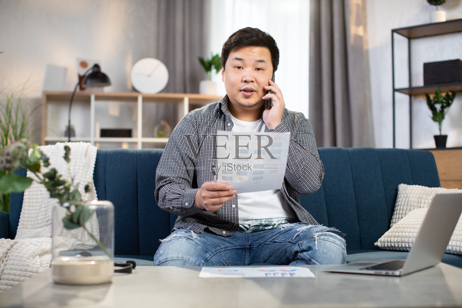 男性自由职业者坐在沙发上用手机聊天照片摄影图片