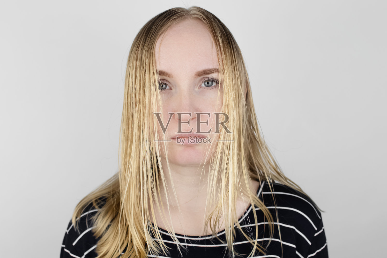 这个女孩看着镜子前她的油光发亮的头发。头皮有问题,皮脂腺分泌增多。头发护理。油性发质的护理和治疗理念照片摄影图片