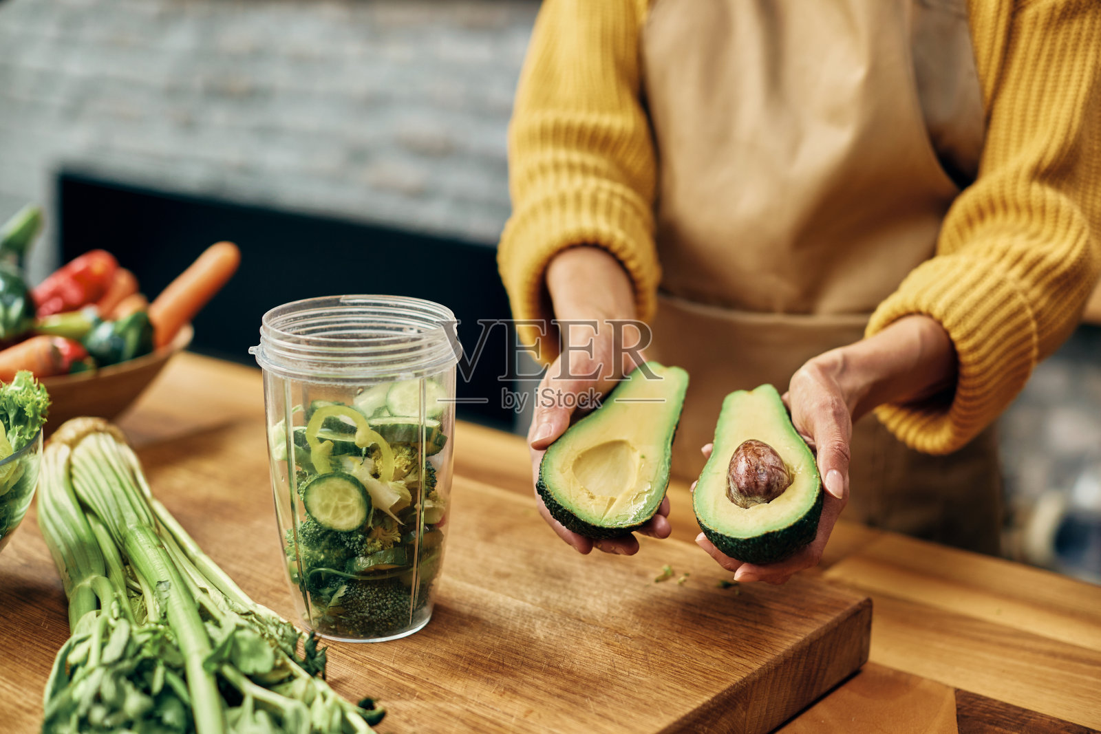 特写的女人使用鳄梨,而准备排毒奶昔在厨房。照片摄影图片
