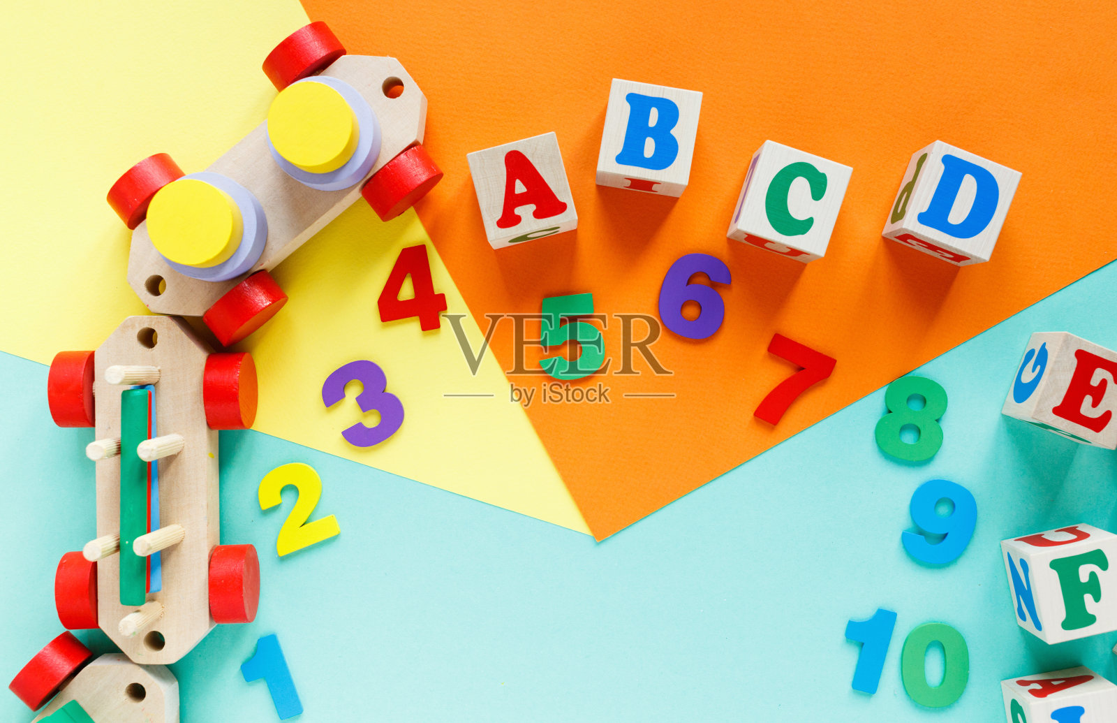 彩色纸上的木制儿童玩具。教育玩具积木,数字,字母,火车。幼儿园、学前班或日托所的玩具。为文本复制空间。俯视图照片摄影图片