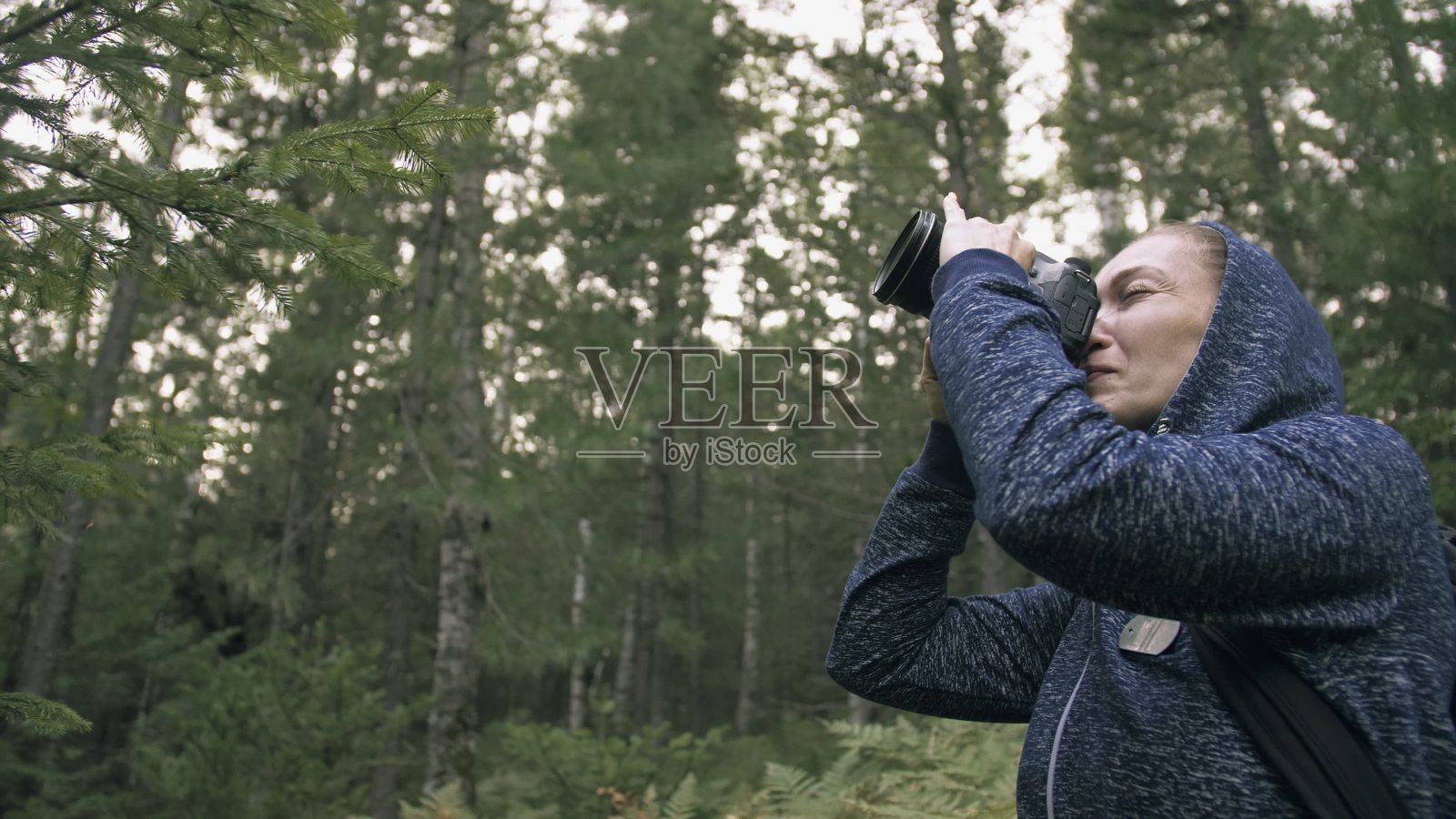 游客在森林中拍摄风景。一名白人女性拍摄了漂亮的魔术。女孩用无反光镜单反相机拍摄视频。照片摄影图片