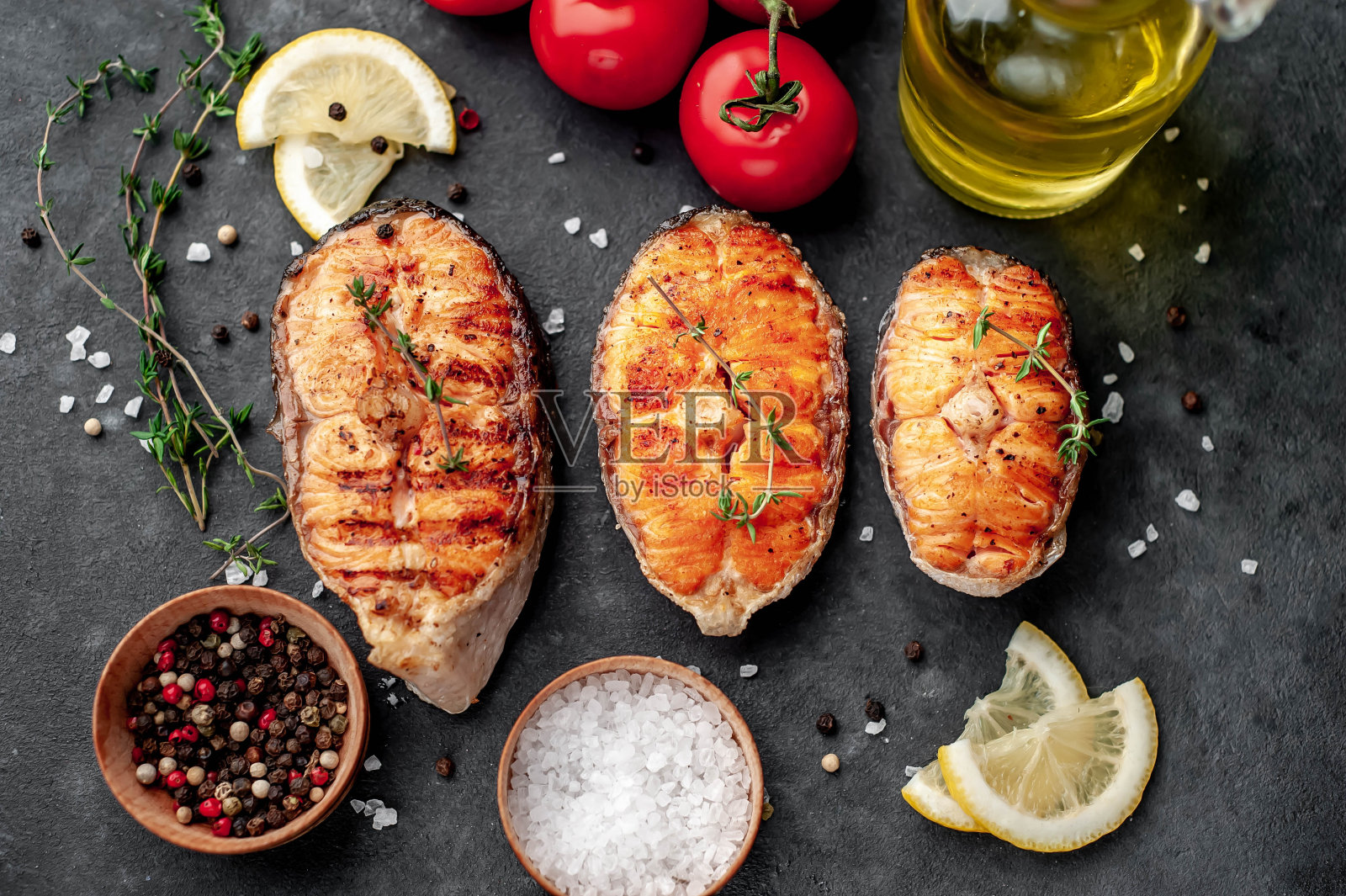 烤鲑鱼排与香料和西红柿在石头背景与复制空间的文本。照片摄影图片