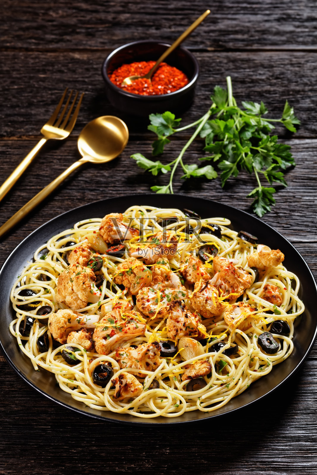 烤花椰菜意大利面配黑橄榄和柠檬皮,放在黑色的木桌上,平铺,空间自由照片摄影图片