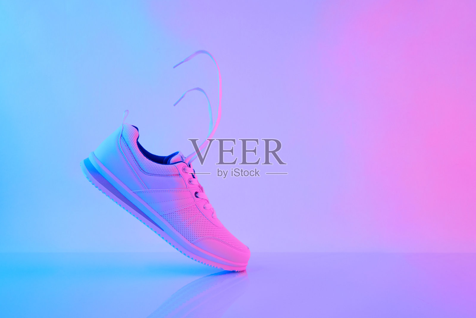 在霓虹的灯光下,拿着白色的鞋带。运动鞋训练在健身房。创造性的极简主义。90年代的概念。照片摄影图片