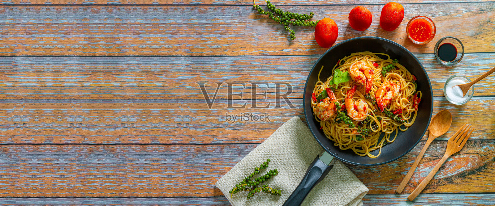 虾仁意大利面,在黑色铁锅里用蔬菜和虾仁炒面条。板岩的背景。关闭了。照片摄影图片