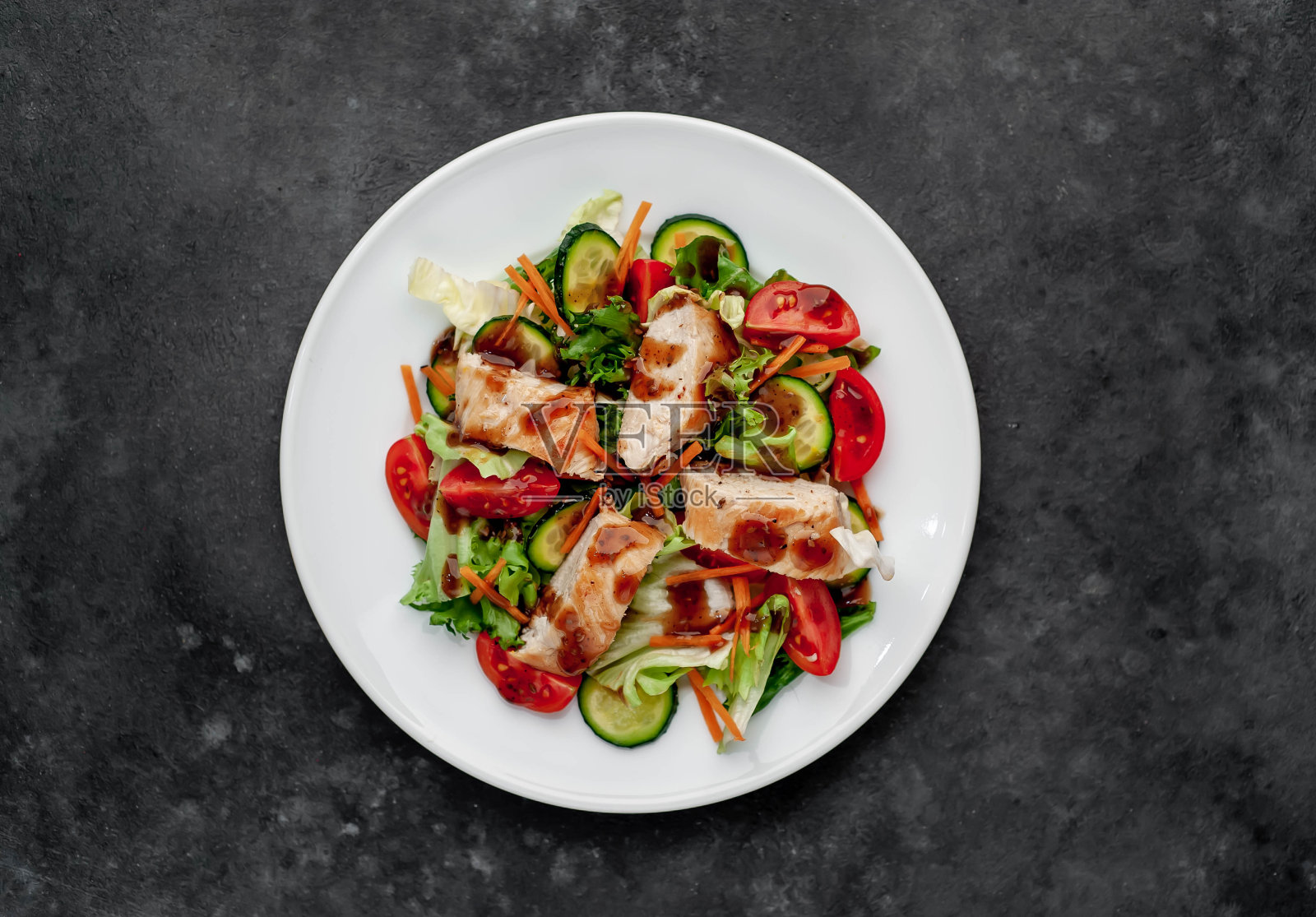 番茄沙拉,鸡肉,黄瓜,胡萝卜,酱油沙拉在一个石头背景的盘子里,为你的文本复制空间照片摄影图片