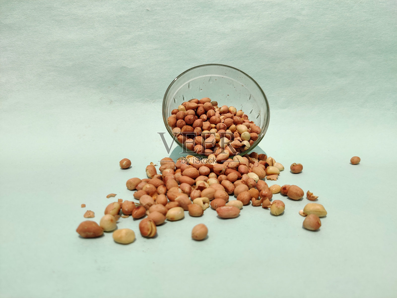 磨碎的坚果从玻璃碗中分离出来,孤立在绿色背景上照片摄影图片