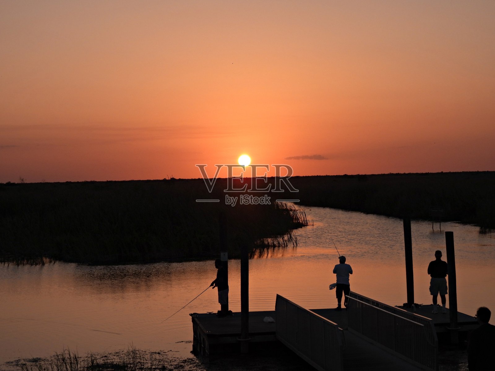 佛罗里达大沼泽地的日落,人们在码头上钓鱼的剪影照片摄影图片