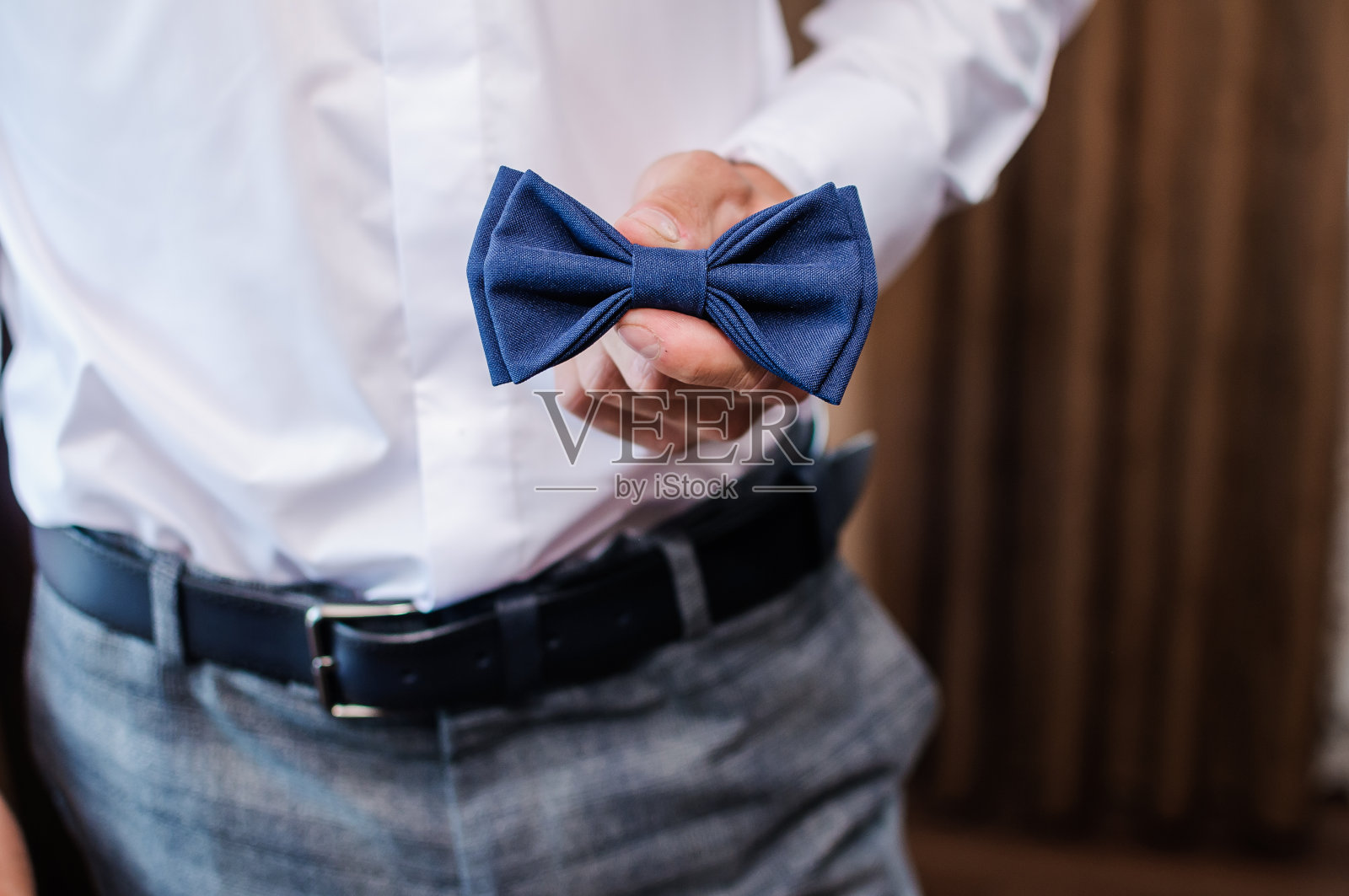 新郎手里拿着蓝色的领结。一个男人的领结照片摄影图片