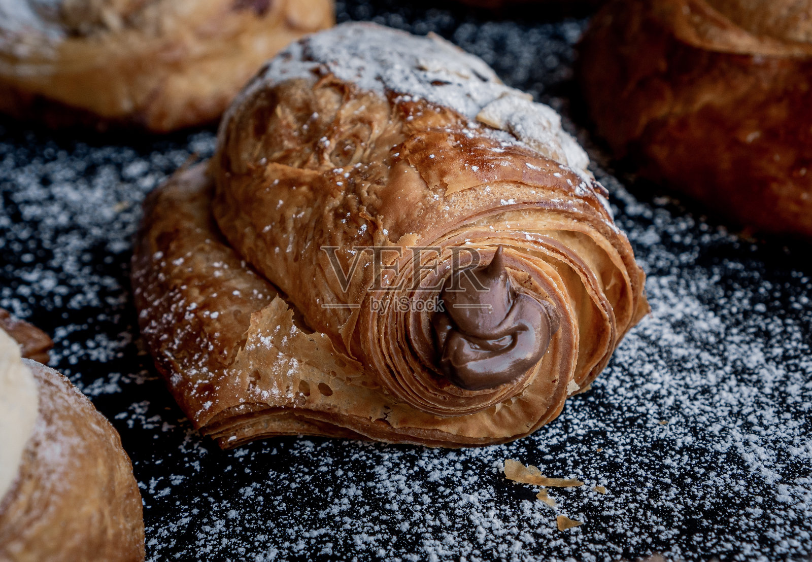 美味的法式杏仁巧克力,充满巧克力在黑色的桌子上装饰着糖。照片摄影图片