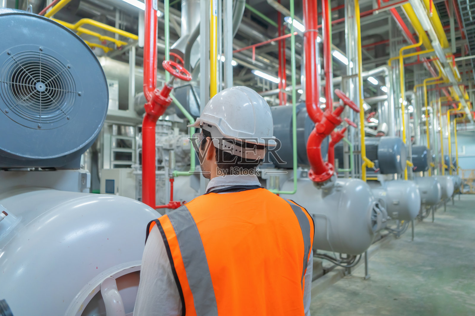 工程师或工人,在工厂工作的人。冷却塔或建筑物中的冷却塔。系统工作的机器。凝汽器供回水管路。通风式压缩机。照片摄影图片