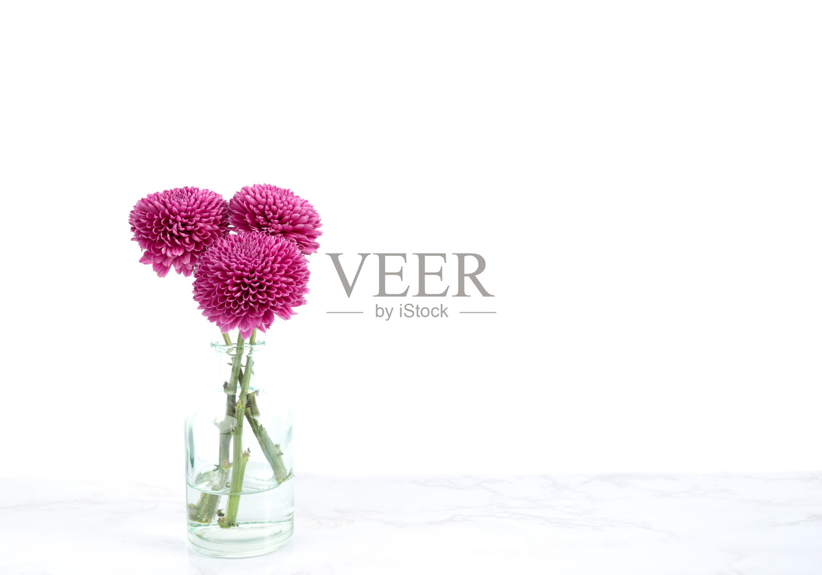 白色墙壁的大理石桌上放着一小束紫色的花照片摄影图片