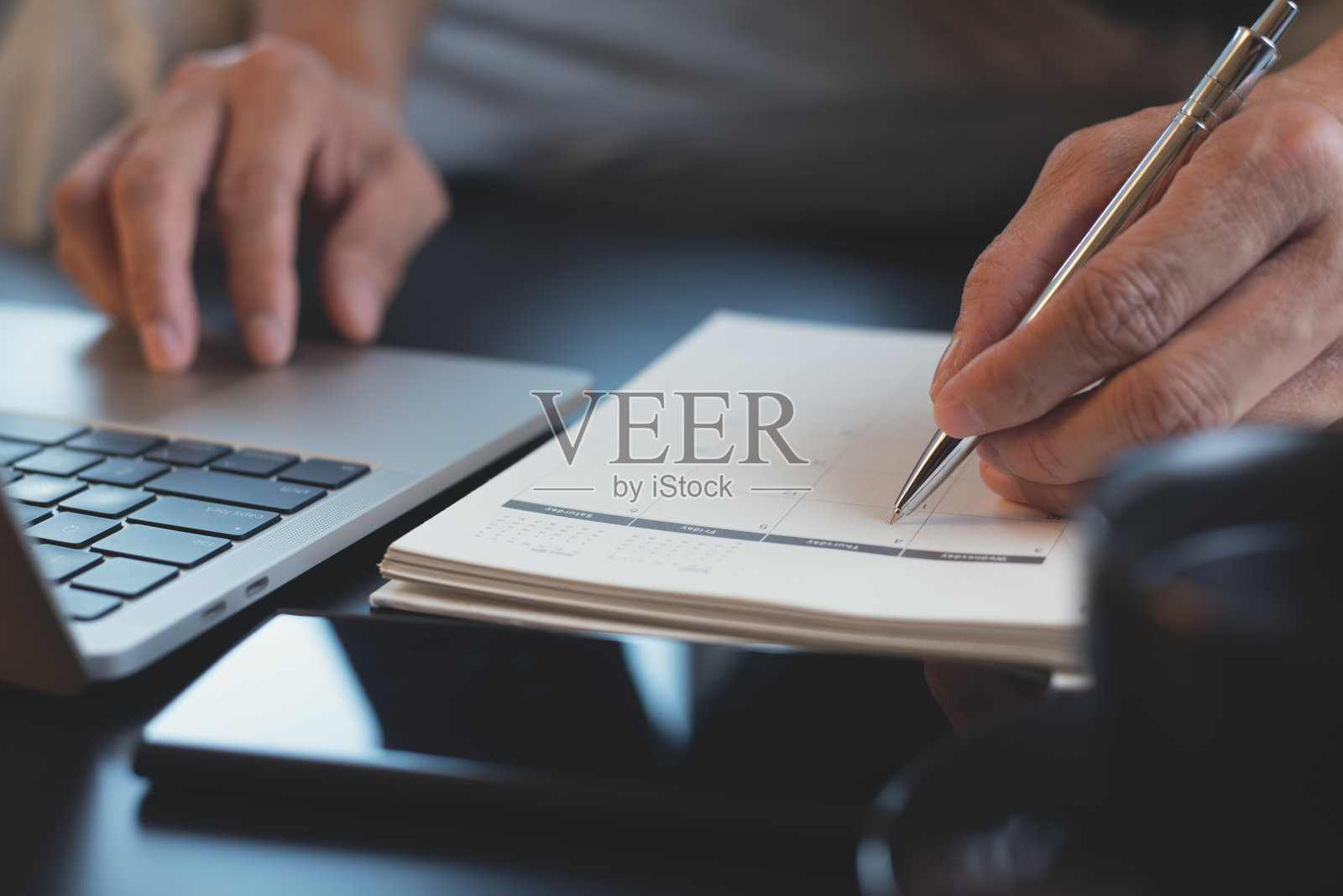 手工记录在日历笔记本和检查工作计划照片摄影图片