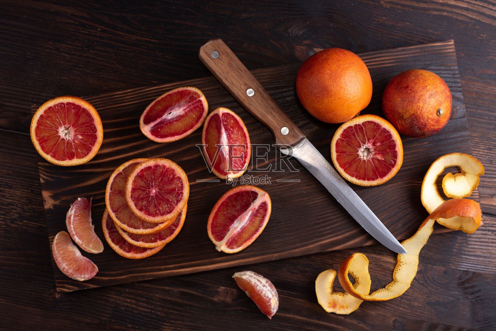 柑橘类水果,血橙在砧板上用刀在一个深色木制背景俯视图。照片摄影图片