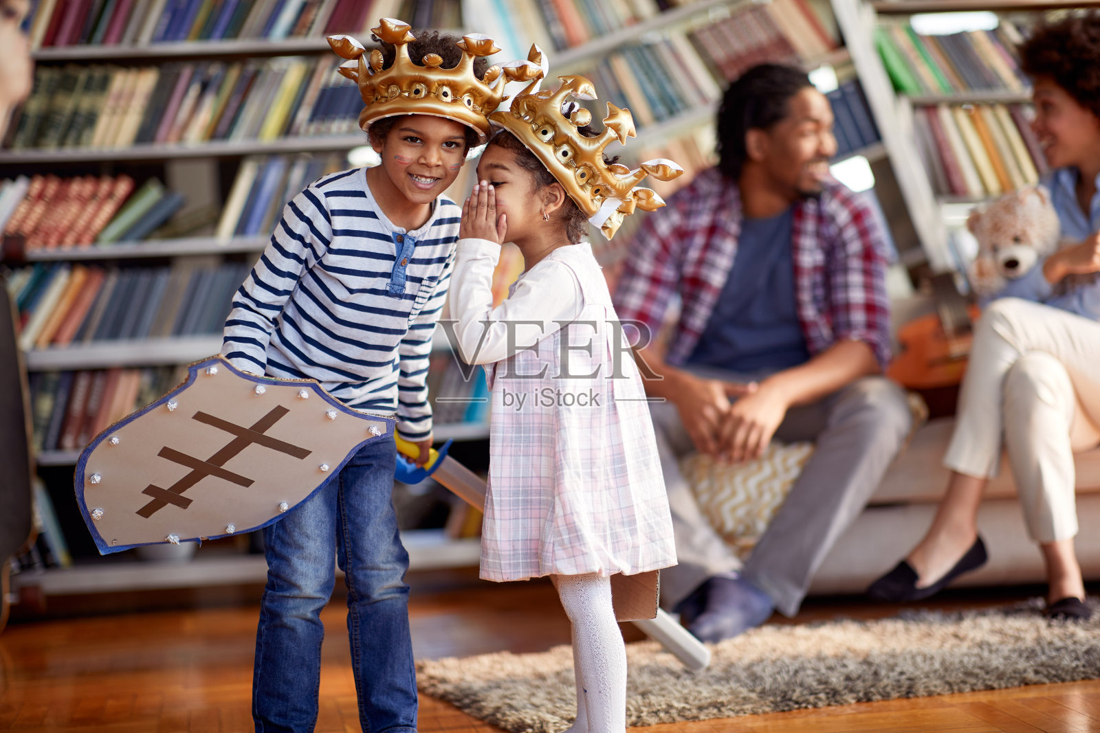 装扮成骑士的孩子们在家里和父母一起玩耍时,低声细语。家庭,家里,游戏时间照片摄影图片