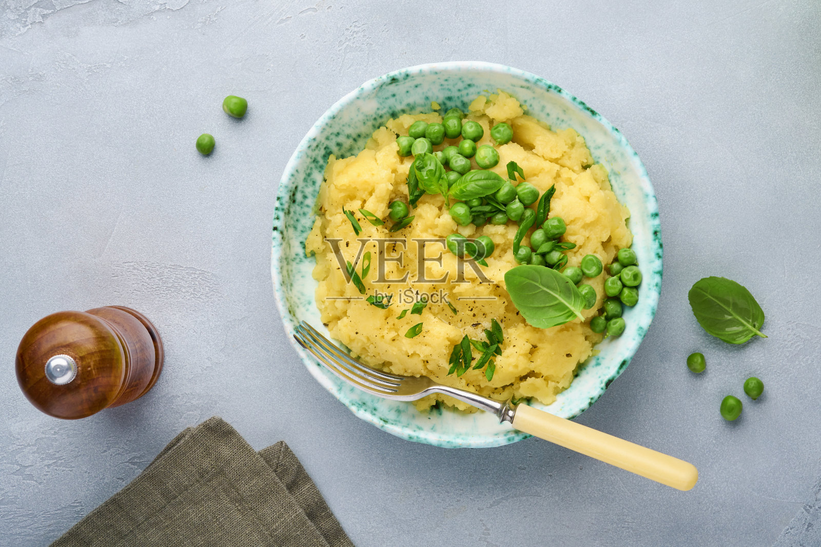 土豆泥,黄油,青豆,洋葱,罗勒放在一个白色的碗里,背景是石板,石头或混凝土。俯视图与近距离。照片摄影图片