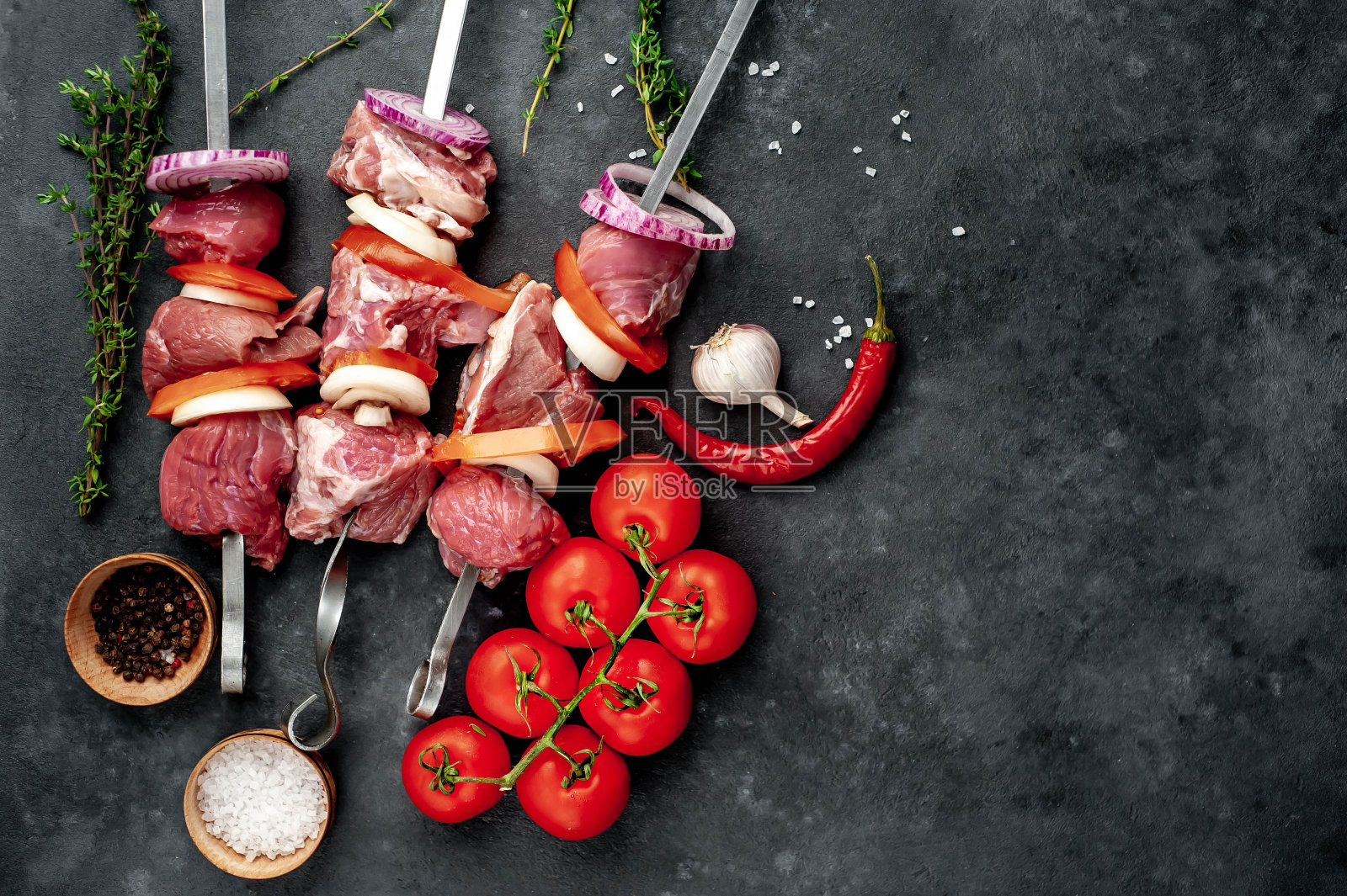 生烤肉串。烧烤肉,蔬菜和香料在一个石头的背景。为你的文本留出空间。照片摄影图片