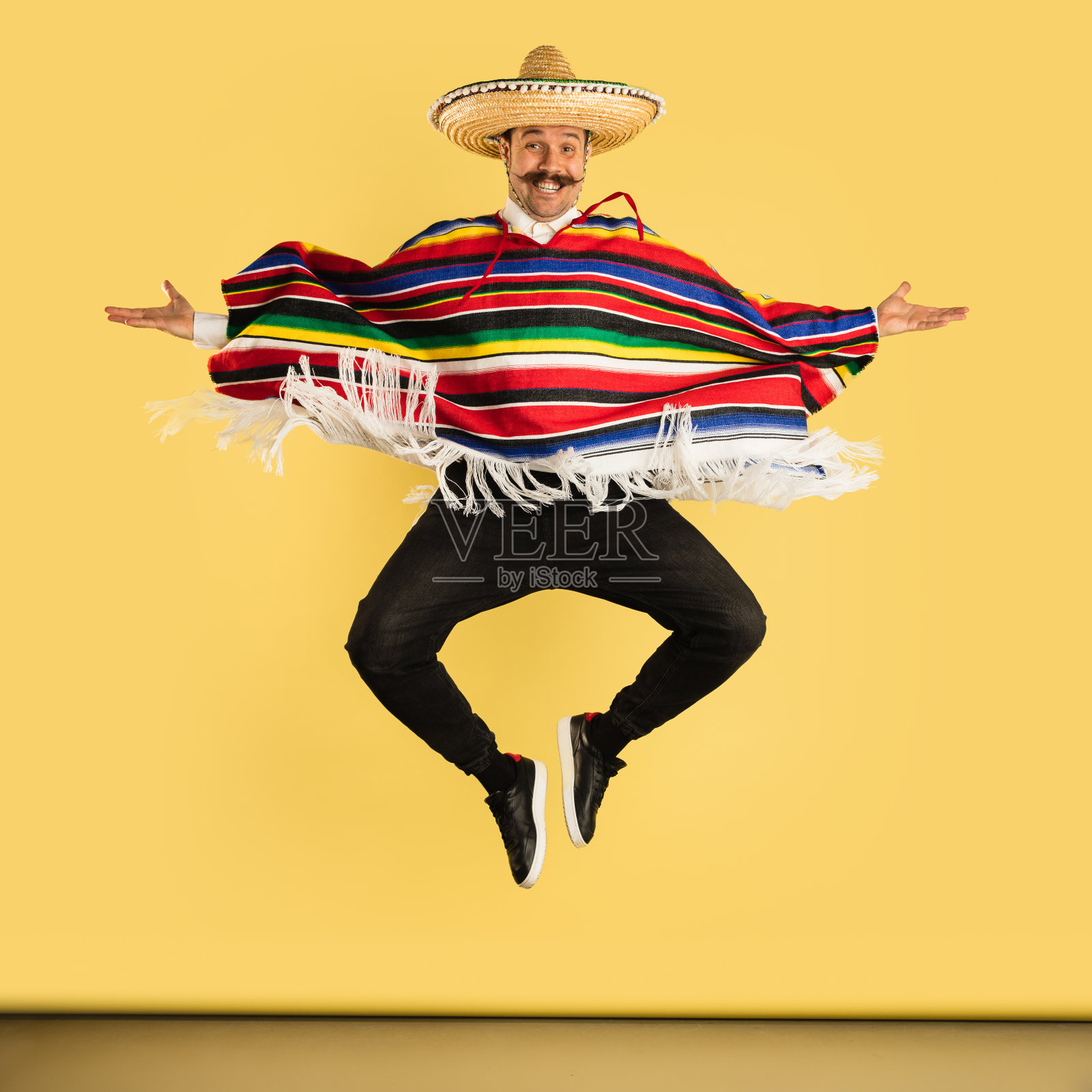 年轻男子在宽边帽和明亮的雨披孤立在黄色背景照片摄影图片