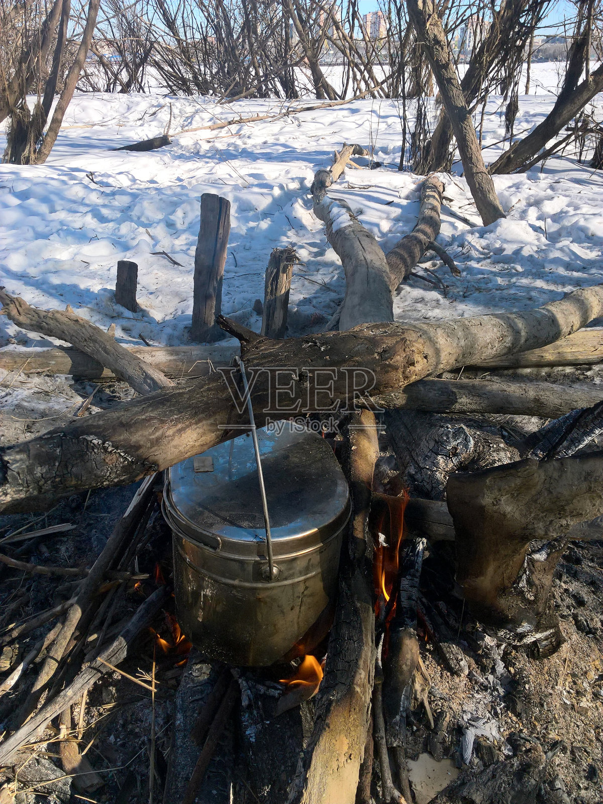 在冬天的森林里,在篝火上用烟熏的旅游锅做饭照片摄影图片
