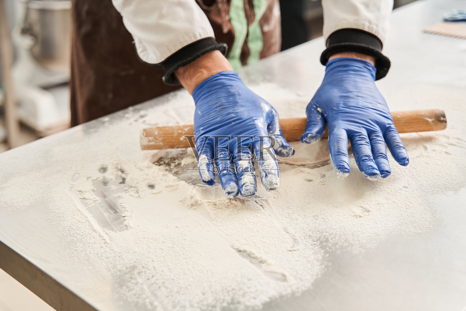 男面包师在桌子上用擀面杖和面粉准备生面团照片摄影图片