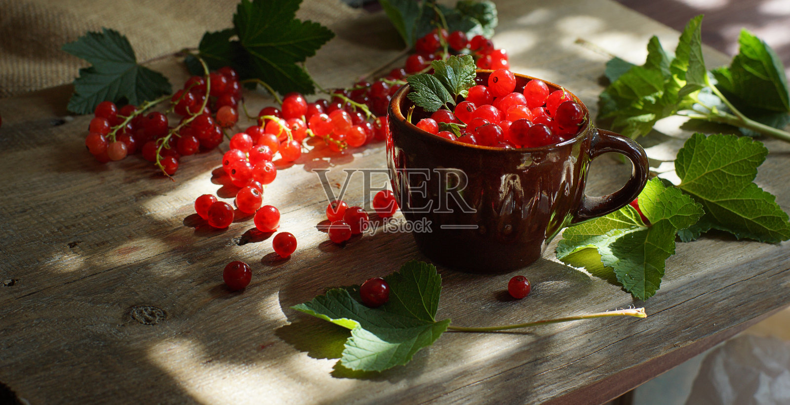 黑板上放着一个棕色的杯子,上面有鲜红的醋栗浆果照片摄影图片