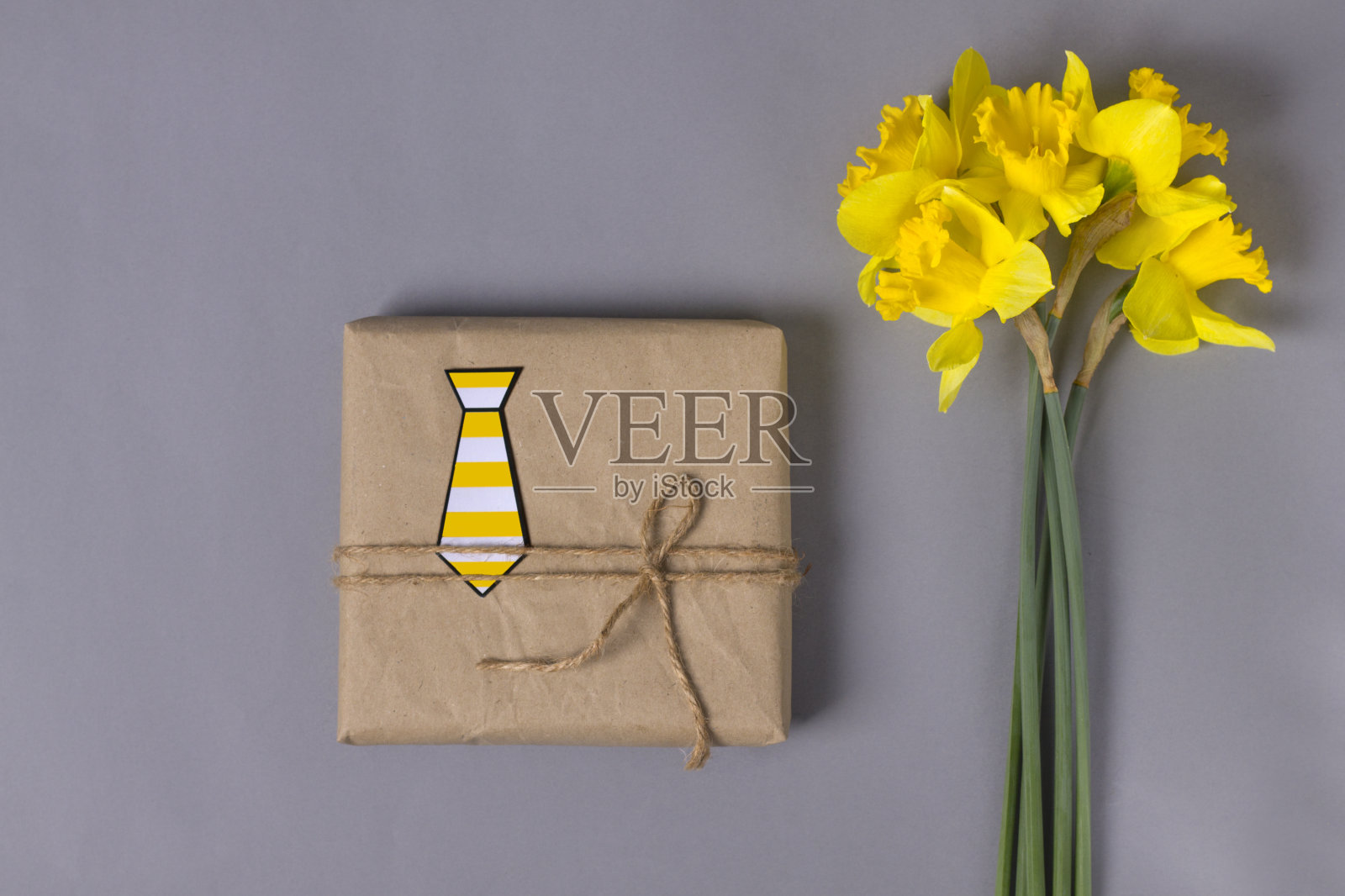 礼物生态盒在灰色的背景与一束黄色的水仙花。平的。父亲节的礼物送给爸爸。男人祝贺的概念。照片摄影图片