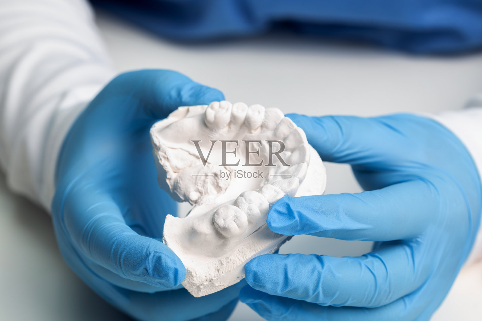 牙医手持牙齿模型,戴着医用手套,制作用于磨牙症、假牙的隐形牙套特写照片摄影图片