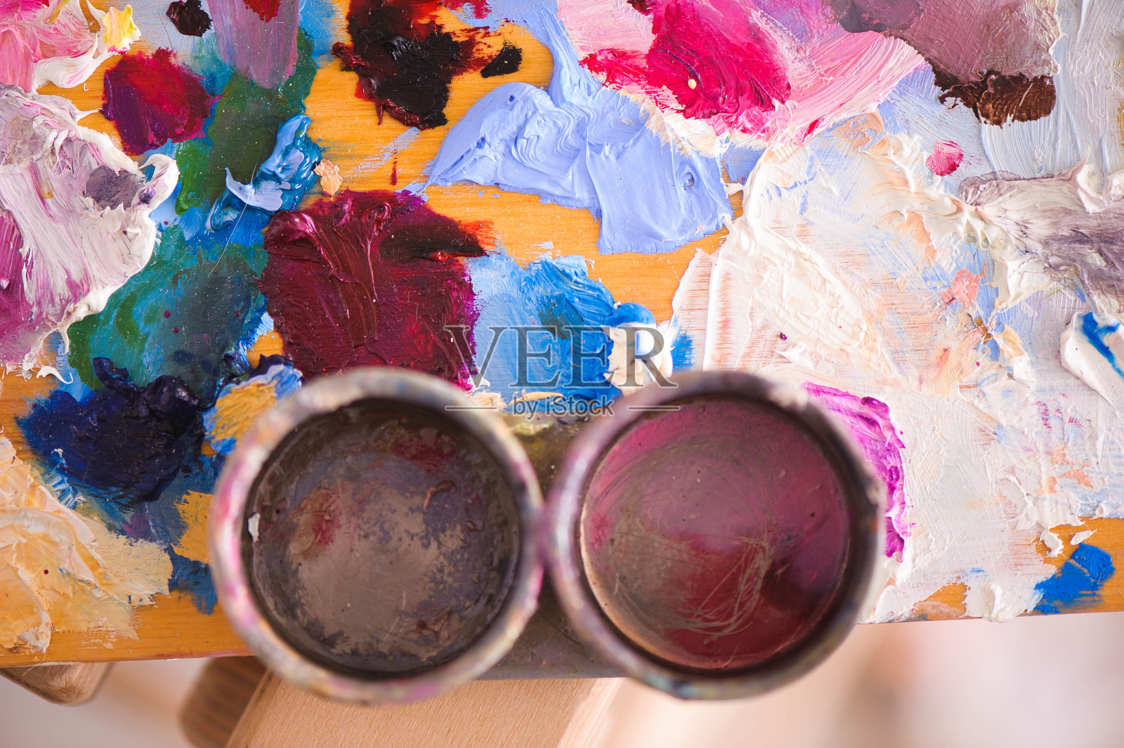 艺术家们在木制的调色板上用画笔和油画作画。照片摄影图片