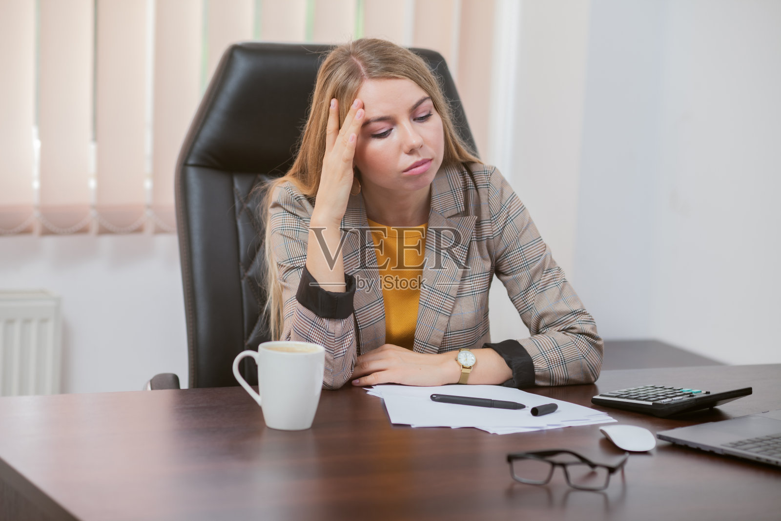 疲惫的女老板坐在办公室的桌子旁照片摄影图片