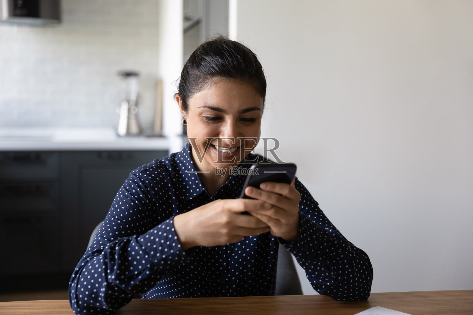 近距离微笑的印度妇女拿着手机,看着屏幕照片摄影图片