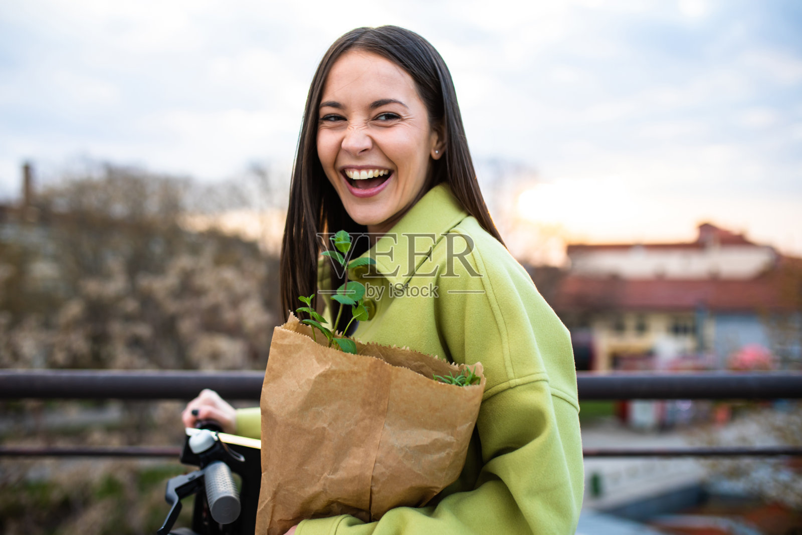 一个漂亮的女人带着一袋食品在电动踏板车上大笑照片摄影图片