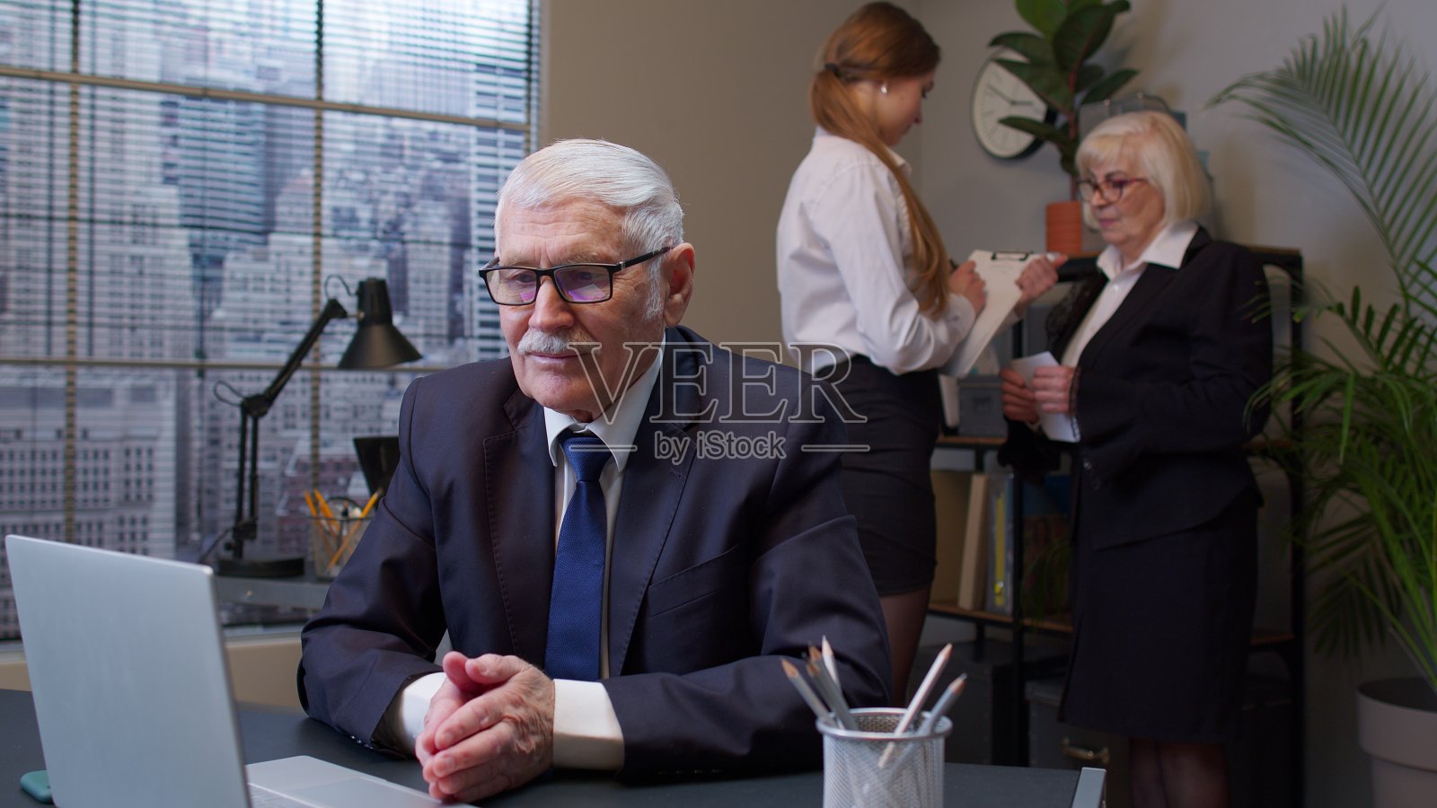 专注于高级商务人士企业家在笔记本电脑上打字做研究,坐在办公桌前照片摄影图片