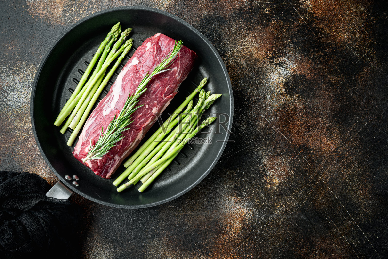 新鲜生的鱼片。整块牛里脊牛排,放在铸铁煎锅上,在旧的深色乡村背景上,俯视图平铺,有文字复制空间照片摄影图片