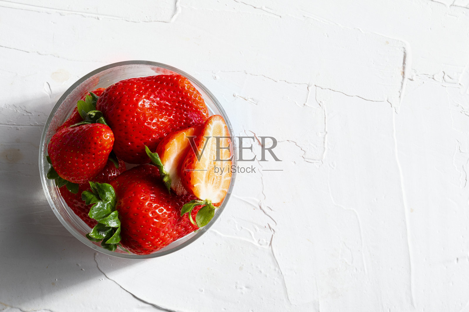 美味可口的红草莓(大草莓)在玻璃碗和薄荷叶(薄荷,薄荷)。在白色纹理背景上。顶部视图与复制空间。照片摄影图片