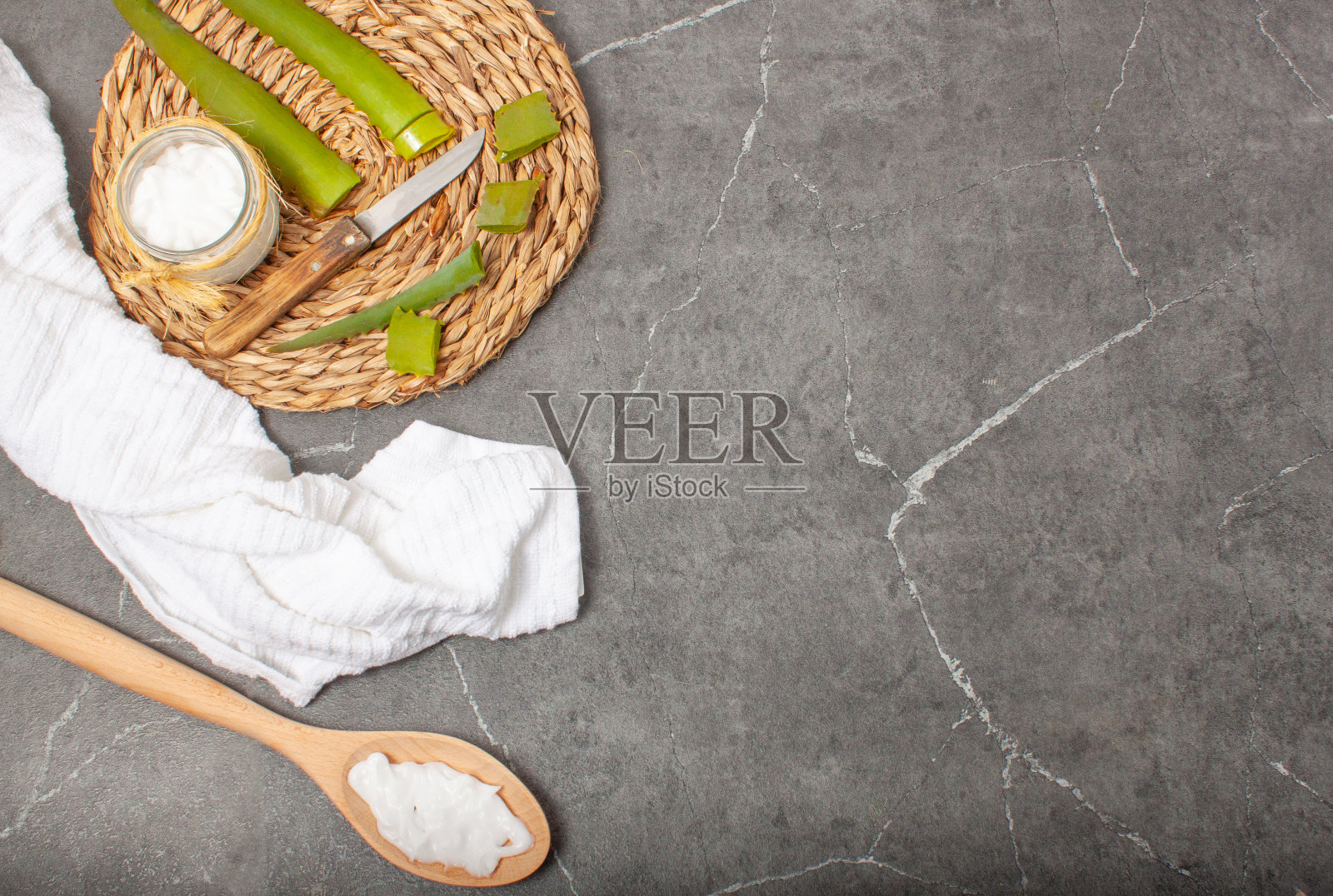 一个用芦荟制成的手霜罐子的静物概念,一个芦荟三角架和一把切芦荟片的刀,使霜与文本的复制空间。照片摄影图片