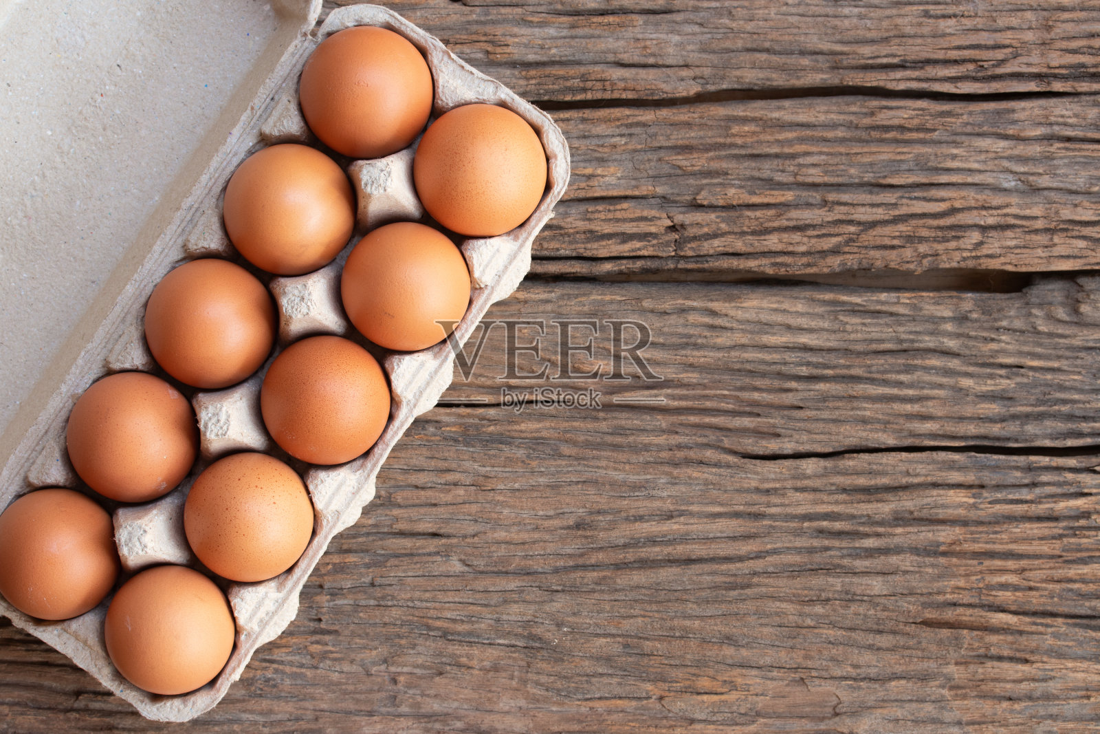 鸡蛋,棕色的鸡蛋装在纸板箱里,放在乡村木桌子上。俯视图鸡蛋在纸板箱。照片摄影图片