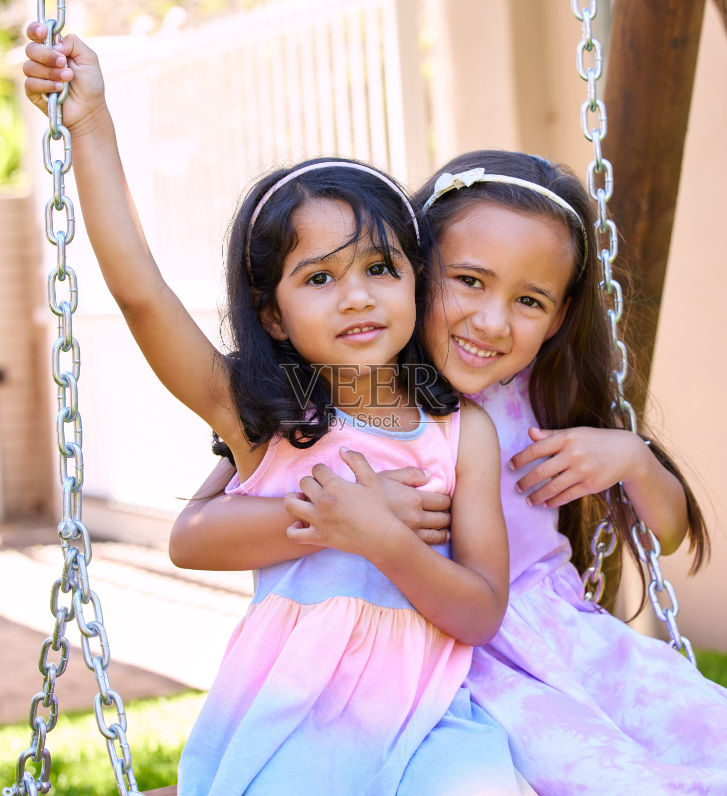 两个小女孩一起坐在秋千上照片摄影图片