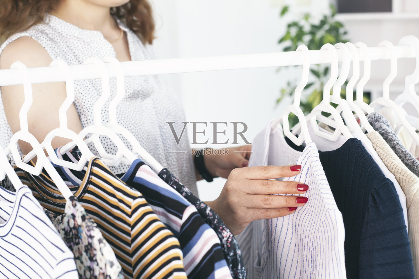 年轻女子在陈列室的衣架上挑选衣服照片摄影图片